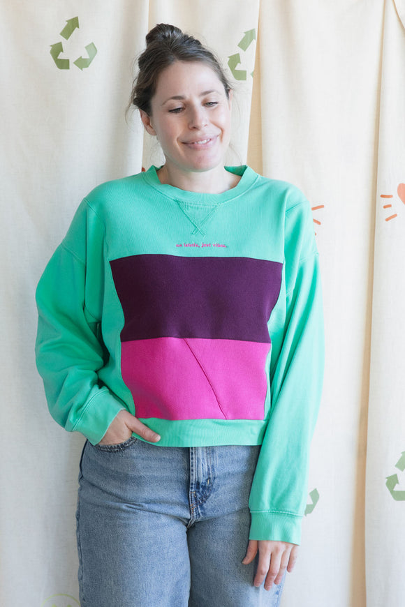 Person wearing a colorful sweatshirt, featuring mint green and pink, upcycled in canada