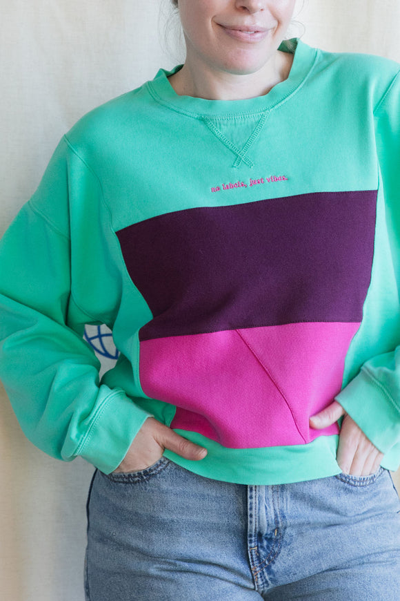 Person wearing a colorful sweatshirt, featuring mint green and pink, upcycled in canada