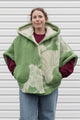 person wearing green wool poncho with oversized hood and fit, featuring pocket up and button up front, upcycled in canada