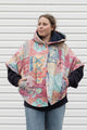 person wearing an oversized poncho, featuring a hood, pockets and button up front, upcycled from a pastel 90's comforter, made in canada