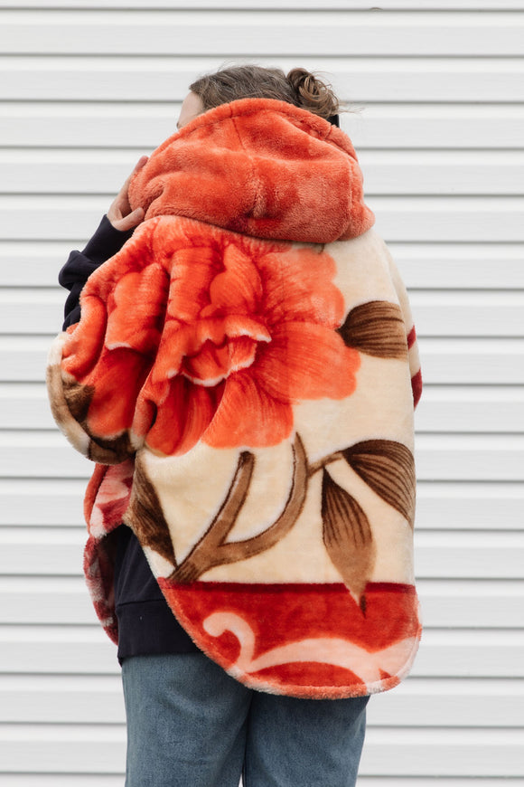 plush orange floral blanket upcycled in to stunning oversized poncho featuring a hood, pockets and button up front, repurposed in canada