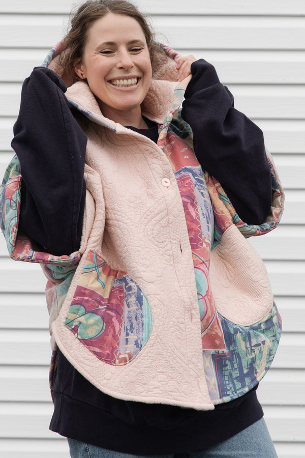 pink quilt and colourful comforter upycled into stunning oversized poncho featuring a hood, pockets and button up front, repurposed in canada