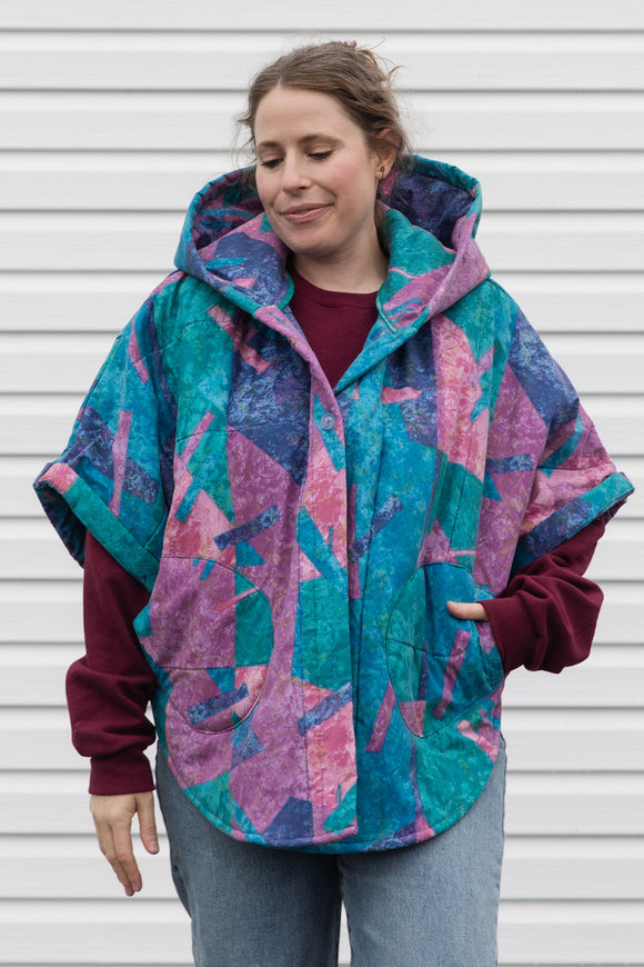 person wearing a colourful poncho jacket, featuring an oversized hood, pockets and a button up front, upcycled in canada