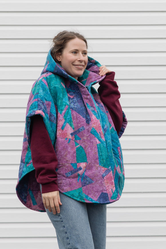 person wearing a colourful poncho jacket, featuring an oversized hood, pockets and a button up front, upcycled in canada