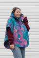 person wearing a colourful poncho jacket, featuring an oversized hood, pockets and a button up front, upcycled in canada