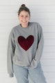 Person wearing a gray sweater with a red velvet heart design against a white background, sewn in canada