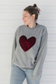 Person wearing a gray sweater with a red velvet heart design against a white background, sewn in canada